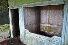 View of a painted wooden box bed, without a mattress, built into a wall of a house