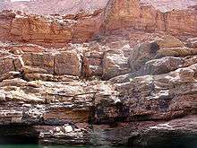 Tan- to cream-colored layer cliff face above water