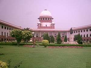 The Supreme Court of India with Green coloured lawn and the building which shows its entrance to the court