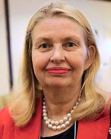 Head-only portrait of a blond woman in her sixties wearing bright red lipstick