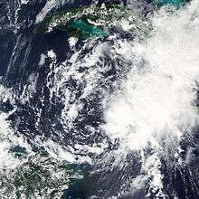 A satellite image of a cluster of storms, weakly circulating about a common center.