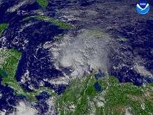 Satellite image of a developing Tropical storm in the central Caribbean Sea. Clouds extend northeast toward Hispaniola and southeast toward northern South America.