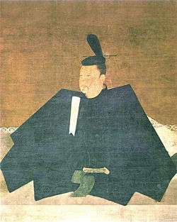Portrait in three-quarter view of a person seated on the floor in courtly attire carrying a stick like object.