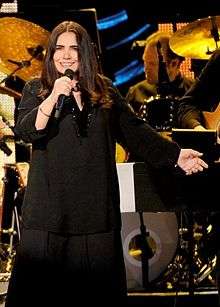 A woman wearing a black dress is holding a microphone