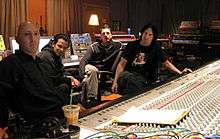 Four men sitting around a large mixing board.