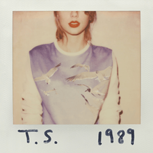 A polaroid of Swift with shoulder-length blonde hair wearing red lipstick and a long-sleeved sweater with a picture of birds in the sky. Her face is cut off by the frame above the nose and "T. S." and "1989" are written on the white polaroid frame with black marker.