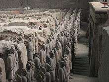 A large number of lined up human sculptures in a pit.