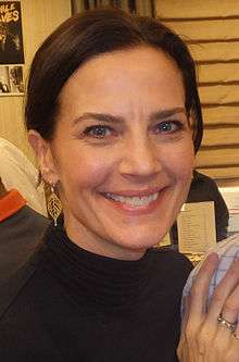 A head and shoulders photo of a white woman with black hair, wearing a black top.