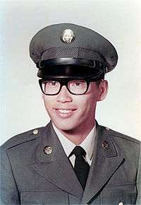 Asian American male wearing Army Dress Green Uniform and glasses posing for a photo.