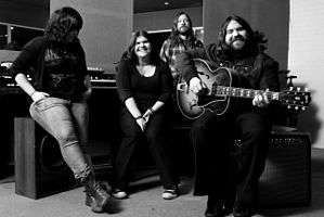 Black-and-white photograph of The Magic Numbers sitting in a recording studio in 2009.