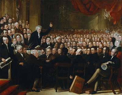 Oil painting of an impressive-looking Victorian man in his fifties enthusiastically addresses a packed hall of men and women.