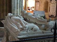 The tomb of the Earl and Countess of Arundel in Chichester Cathedral, which is topped by a life-size sculpture of the couple. An unusual feature of the sculpture is central to Larkin's poem "An Arundel Tomb": "Such plainness of the pre-baroque / Hardly involves the eye, until / It meets his left-hand gauntlet, still / Clasped empty in the other, and / One sees, with a sharp tender shock, / His hand withdrawn, holding her hand"