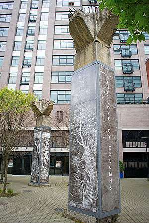 Two columns in an urban plaza, displaying reproduced artwork; in the background is the exterior of a building