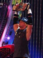 Photograph of The Real World: Back to New York cast member Mike Mizanin holding up a World Wrestling Entertainment champion belt in 2008