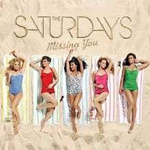 Five women lie on striped towels on a beach. Each is wearing a different coloured short dress. Above them, written in the sand, is the name of the group (The Saturdays) and the name of the single (Missing You).