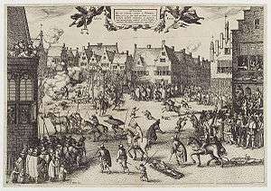 A monochrome illustration of a busy urban scene. Medieval buildings surround an open space, in which several men are being dragged by horses. One man hangs from a scaffold. A corpse is being hacked into pieces. Another man is feeding a large cauldron with a dismembered leg. Thousands of people line the streets and look from windows. Children and dogs run freely. Soldiers keep them back.