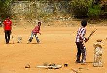 Three Hyderabadi boys playing with cricket bats and a ball