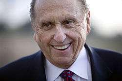 Close-up of older, wrinkled man in conservative suit smiling