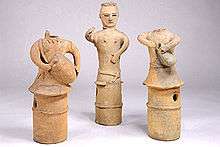 Three clay figures called haniwa, two of which depict figures playing drums.
