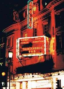 A neon sign for a stage play at the Apollo Theatre reads "Andrew Dawson - Gavin Robertson - Thunderbirds FAB - A Forbidden Planet Production"