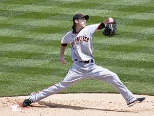 Tim Lincecum, wearing a black baseball cap and grey baseball uniform with the words SAN FRANCISCO across, delivers a pitch
