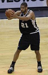 A man of lighter complexion holds a basketball while playing in a basketball game.