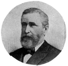 A black and white circular portrait of a Caucasian man in a suit and bow tie.