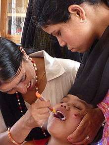 Nepalese women examining patient's mouth in oral health clinic