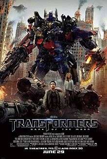 The poster depicts a Transformer named Optimus Prime, standing with a blade in his left arm, and a blaster in his right arm. There is also a young couple standing below the Transformer, and just where the 3 are standing, there is also a crash-landed Decepticon fighter. Behind the Transformer and the couple, there is a war-torn city of Chicago, with Decepticon battleships surrounding it. The film title and credits are on the bottom of the poster.