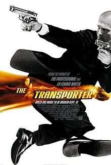 Jason Statham wearing a suit and holding two guns, in black and white.  A band of orange colour with the title Transporter is overlaid in the middle of the picture.