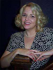 A woman with blond hair, wearing a black and white outfit.