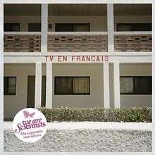 A photo taken from beside some sort of apartment complex. The words "TV EN FRANCAIS" are inscribed on the side of a balcony. A pink "We Are Scientists" logo is located in the bottom left with the subtext "The expensive new album".