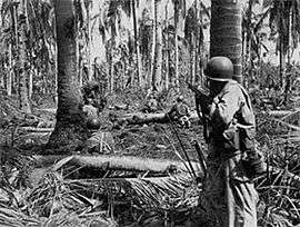 Two soldiers hiding behind trees while moving through a thick groove of jungle