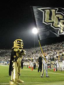 UCF's black and gold clad mascot, Knightro, on the field during a football game.