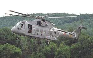 Five-bladed gray helicopter landing in the middle of bush land