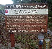 A brown wooden plaque with "White River National Forest" inscribed across the top and explanatory text about the Independence Townsite below