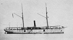 broadside view of a two-masted schooner with a smoke stack in the center, at anchor, without sails, painted white