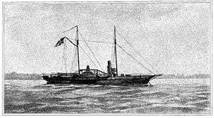"Black and white image of USS Hetzel from a watercolor painting. She lies at anchor, her clipper bow to the right. She carries two masts; a large American flag flies from the gaff of the after (main) mast. The starboard sidewheel is a little aft of directly midship. The single stack is about equally far forward. Superstructure includes a pilot house forward of the stack, some parts of the engines, and a row of cabins aft of the stack. One gun is mounted on the main deck forward, and another is at the stern."