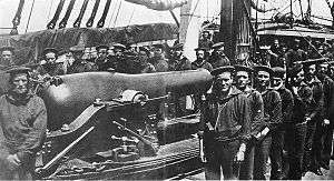 A group of twenty-six sailors posing around a rifled naval cannon.