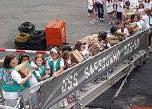 Girl Scouts and Brownies from two troops in Singapore pass Girl Scout cookie boxes up the brow of the rescue and salvage ship USS Safeguard (ARS 50) as part of Operation Thin Mint