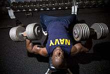 A navy man performs strength training exercises.