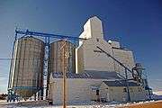 Grain elevator on snow, against a blue sky