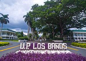 A sign in the foreground reads "P. P. Los Baños; several buildings are seen in the background