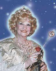 A smiling, framed, old woman with a wand, behind her the starry sky.