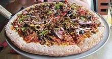 A medium pizza covered in vegetables on a wooden table