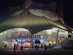 A white illuminated building that resembles a circus tent
