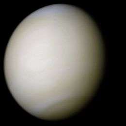 Venus in approximately true colour, a nearly uniform pale cream, although the image has been processed to bring out details. The planet's disc is about three-quarters illuminated. Almost no variation or detail can be seen in the clouds.