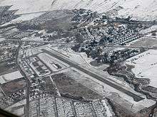 An aerial view of an airport on a snowy day, containing a runway.