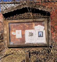 Wooden notice board labeled "Vinegar Hill", with several flyers for community events under glass.