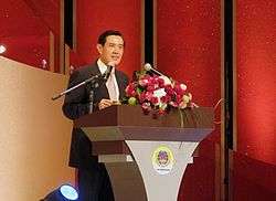 Ma Ying-jeou stands behind a podium decked with flowers